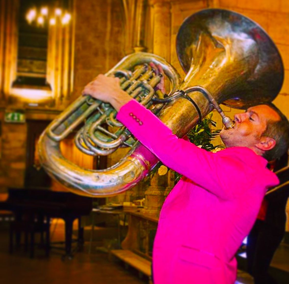 Nathan Gash playing the tuba in a bright pink suit